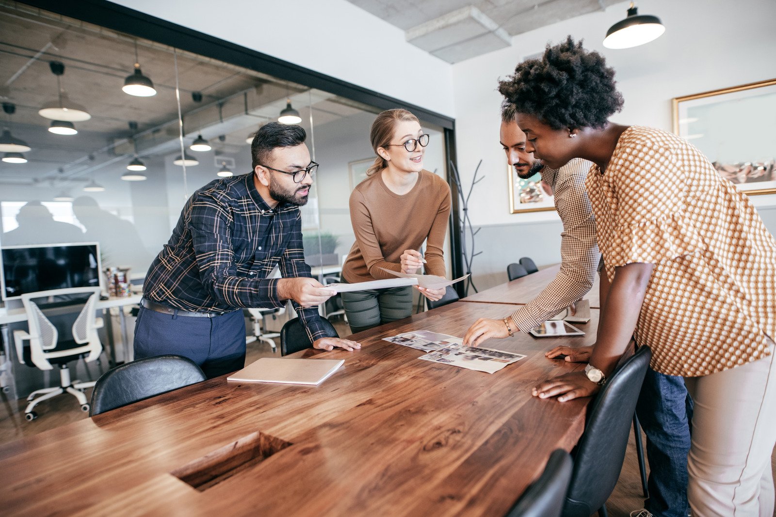 A diverse team of professionals collaborating around a laptop in a modern office.